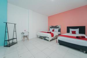 um quarto com 2 camas e uma parede rosa em RedDoorz Syariah at MN One Cempaka Putih em Jakarta
