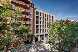 un edificio alto de ladrillo con árboles delante de él en Aparthotel Napols - Abapart, en Barcelona