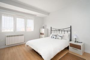a white bedroom with a large bed and windows at MyHouseSpain - Moderno piso frente al mar in Gijón