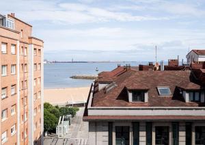ヒホンにあるMyHouseSpain - Moderno piso frente al marの建物の屋根からビーチの景色を望めます。