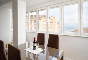 a glass table with chairs and a bottle of wine on it at MyHouseSpain - Moderno piso frente al mar in Gijón