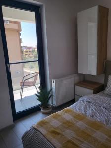 sypialnia z łóżkiem i oknem z krzesłem w obiekcie Mara Apartment w mieście Năvodari