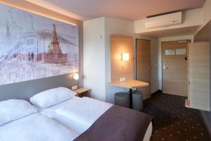 um quarto de hotel com uma cama e um quadro na parede em B&B Hotel Heidelberg em Heidelberg