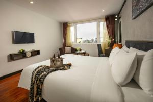 a hotel room with a large white bed and a television at Hanoi La Palm Premier Hotel & Spa in Hanoi