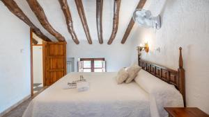 ein Schlafzimmer mit einem großen weißen Bett in einem Zimmer mit Holzbalken in der Unterkunft Cortijo Alzamigaja Archidona by Ruralidays in Archidona + 30 Fotos