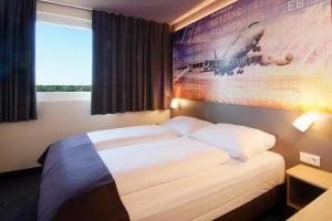 sypialnia z łóżkiem z plakatem na ścianie w obiekcie B&B Hotel Frankfurt-Airport w Frankfurcie nad Menem