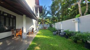 a house with a yard with chairs and a patio at Villa Crimson Bay in Unawatuna