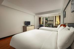 een slaapkamer met een groot wit bed en een televisie bij Hanoi La Palm Premier Hotel & Spa in Hanoi