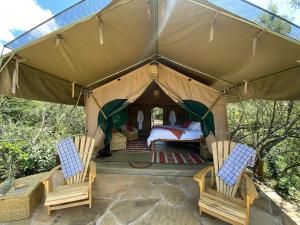 a tent with two chairs and a bed in it at Echoes of Eden: Forest Haven in Melewa