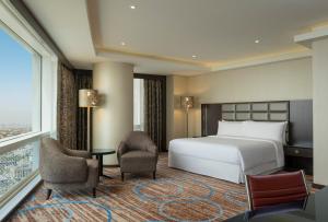 a hotel room with a bed and chairs and a window at Four Points By Sheraton Kuwait in Kuwait