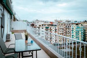 einen Balkon mit einem Tisch und Stühlen sowie eine Stadt in der Unterkunft Eunoia Luxury Apartment Thessaloniki in Thessaloniki