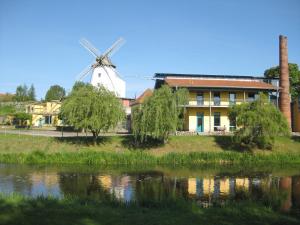a windmill and a house next to a river at Doppelzimmer 13 Gästehaus Mühlenstein in Bad Sülze