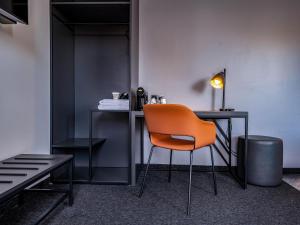 einen orangenen Stuhl an einem Schreibtisch in einem Zimmer in der Unterkunft B&B Hotel Villingen-Schwenningen in Villingen-Schwenningen