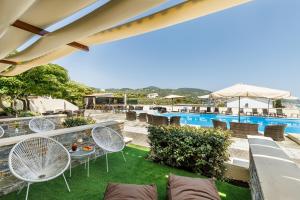 an outdoor patio with tables and chairs and a swimming pool at Skopelos Holidays Hotel & Spa in Skopelos Town