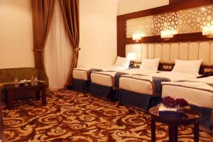 a hotel room with three beds and a couch at فندق الاندلس الماسى in Al Madinah