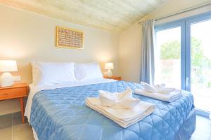 a bedroom with a blue bed with towels and a window at Villa Aphrodite in Pouládes +39 photos