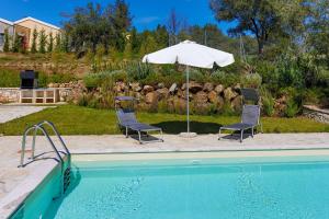 two chairs and an umbrella next to a swimming pool at Villa Aphrodite in Pouládes
