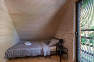 a small bed in a wooden room with a window at Po prostu Piękna! Domek nad jeziorem in Stare Jabłonki