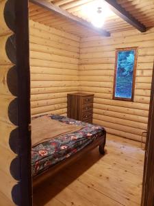 ein Schlafzimmer mit einem Bett in einem Blockhaus in der Unterkunft Cottage Sochi in Ambrolauri