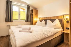 a bedroom with a large white bed with towels on it at Alpha Apartments in Schwarzach im Pongau