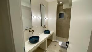 a bathroom with two blue sinks and a mirror at Skiathos Ammos Luxury Apartments in Skiathos