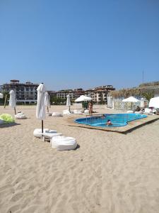 une plage de sable avec 2 piscines et des parasols dans l'établissement Oasis Resort & Spa 1 bedroom 5.3.А Stanis, à Lozenets