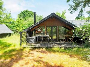 a cabin in the woods with a deck and a table at Holiday home Glesborg LXIII in Glesborg
