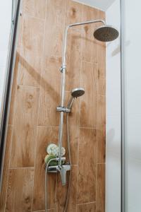 a shower in a bathroom next to a wooden wall at Noclegi Przy Stacji in Nowy Dwór Mazowiecki