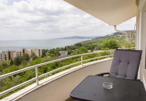 una silla en el balcón con vistas al agua en Two Identical Designer 2BD Flats with Sea View in Balchik by Flat Mаnager, en Balchik