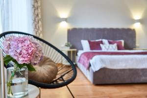 a bedroom with a bed and a chair with a vase of flowers at Best Apartments on Kyryla & Mefodia in Mukacheve