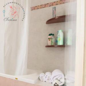a bathroom with a shower curtain and towels on a shelf at SERINA TROPEA in Tropea