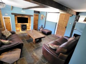sala de estar con muebles de cuero y chimenea en Castle Hill Cottage on a Scheduled Monument en Kenilworth