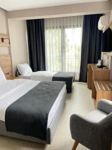una habitación de hotel con 2 camas y una silla en Palmon Hotel en Erdek