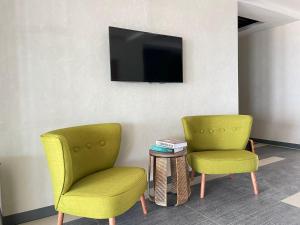 twee stoelen en een tafel met een tv aan de muur bij Palmon Hotel in Erdek