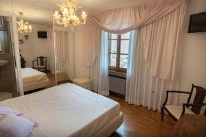 1 dormitorio con cama, ventana y lámpara de araña en B&B Il Chiostro Assisi, en Asís