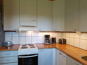 Una cocina con gabinetes blancos y un horno de estufa. en Poronpolku, en Syöte