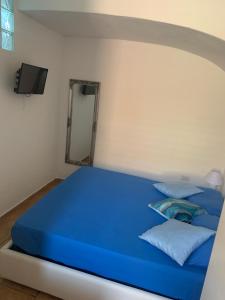 a blue bed in a white room with a mirror at Casa Balilla 2 in La Maddalena