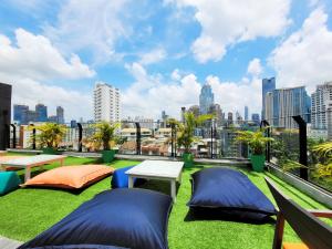 a rooftop patio with two picnic tables and grass at Citrus Suites Sukhumvit 6 by Compass Hospitality in Bangkok