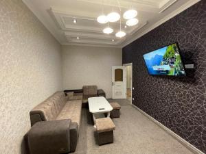 uma sala de estar com um sofá e uma televisão na parede em Central Apartment em Samarkand