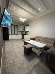 uma sala de estar com um sofá e uma televisão em Central Apartment em Samarkand
