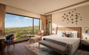 斋浦尔Taj Devi Ratn Resort & Spa, Jaipur的一间带床和大窗户的卧室