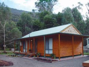 a small wooden cabin with a porch and trees at Kiramli Villas in Halls Gap