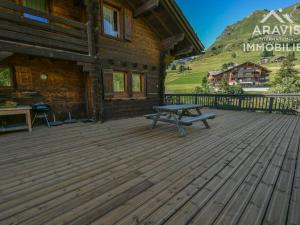a wooden deck with a picnic table in front of a cabin at Chalet Le Grand-Bornand, 8 pièces, 16 personnes - FR-1-391-33 in Le Grand-Bornand