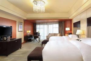 a hotel room with white beds and a television at Wyndham Grand Plaza Royale Hangzhou in Hangzhou