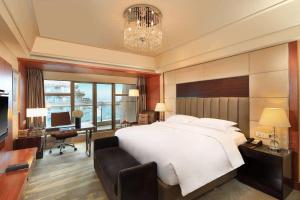a bedroom with a large white bed and a desk at Wyndham Grand Plaza Royale Hangzhou in Hangzhou
