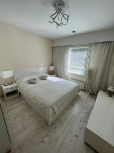 a white bedroom with a bed and a window at Raita Villa in Savonlinna