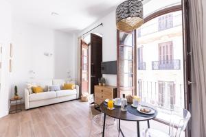 a living room with a white couch and a table at Apartamento-Loft Especería Black in Málaga