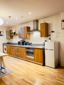 una cucina con armadi in legno e frigorifero bianco di Beautiful Central Open plan living! a Manchester