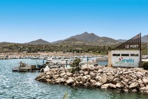 a marina with a building and rocks in the water at Hotel Centre Plage in Argelès-sur-Mer