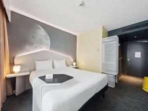 a bedroom with a large bed with a moon painted on the wall at ibis Styles Paris Charles de Gaulle Airport in Roissy-en-France